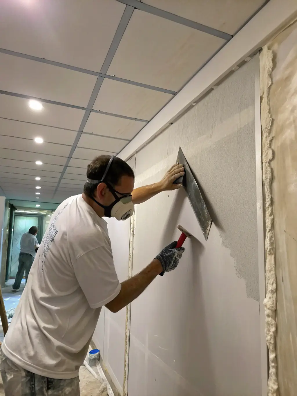 A skilled drywaller smoothing out drywall seams in a newly constructed room, ensuring a flawless finish.